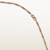 A detailed view of an 18k rose gold chain with elongated textured links and an “S” link clasp.