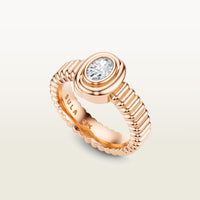 A gold 18k rose gold ring featuring a textured band and bezel-set white diamond. 