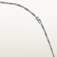 A detailed view of an 18k white gold chain with elongated textured links and an “S” link clasp.