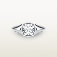 An 18k white gold ring featuring a cushion-cut diamond in a soft bezel setting, with a smooth, tapered band.