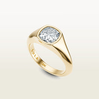 A cushion-cut diamond set in a bold 18k yellow gold bezel ring, engraved with “SULA 18K” on the inside of the band.