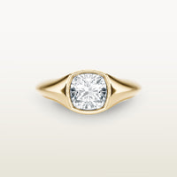 An 18k yellow gold ring featuring a cushion-cut diamond in a soft bezel setting, with a smooth, tapered band.
